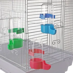 Detail shot of automatic bird waterers in green, blue, and pink attached to a cage