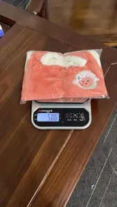 Gilet en peluche rose pour animal pesant cinquante grammes sur une balance