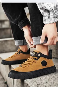 Detail of retro tan suede men's sneakers with thick black soles and lacing detail.