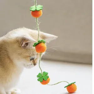 Primo piano di un gattino che gioca con un giocattolo per gatti in feltro arancione