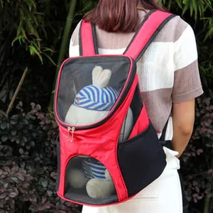 Detail view of a red pet carrier backpack with breathable mesh windows worn by a person.