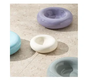 Sammlung von Keramiknäpfen in Donutform in zarten Pastellfarben auf Terrazzoboden.