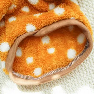 Close-up detail of soft orange polka dot fleece pet clothing with ribbed cuff