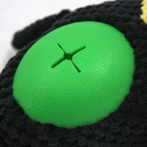 Close-up detail of green rubber treat dispenser on a black plush parrot dog toy for pets
