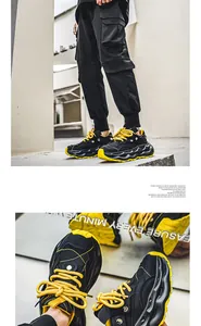 Detailed view of men's chunky black sneakers with vibrant yellow soles and thick cushioning.