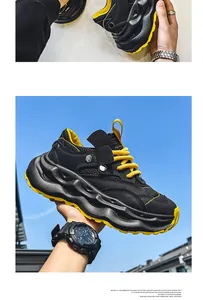 Detailed side profile of black and yellow breathable chunky sneakers held against the blue sky