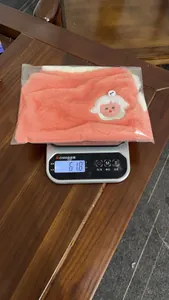 Gilet doux en peluche rose pour animal pesé sur une balance électronique affichant 61,8 g