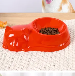 Detailaufnahme eines leuchtend orangefarbenen Katzenfressnapfes auf weißer Matte