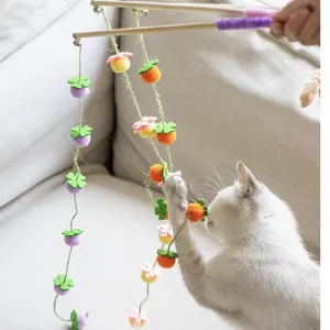 Vista dettagliata di una bacchetta per gatti con palline di feltro e un gatto bianco