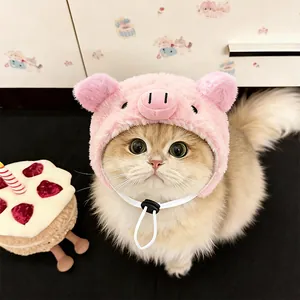 Close-up view of a cute pink plush pig-shaped hat on a cat with an adjustable strap detail