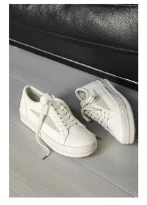 Vue détaillée de baskets en cuir blanc pour hommes posées sur un sol gris