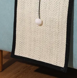 Detail view of a durable sisal cat scratching mat with white plush ball for sofa protection