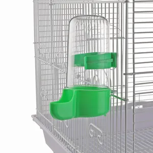 Detail view of a green automatic bird water feeder attached to a white wire cage