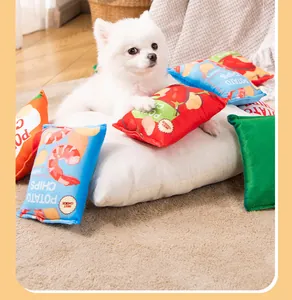 White puppy lying on a cushion surrounded by plush potato chip pet squeaky toys