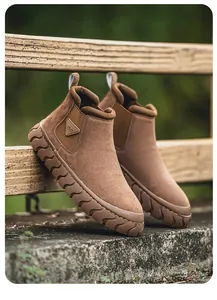 Gros plan de bottes montantes en daim marron sur une clôture en bois rustique