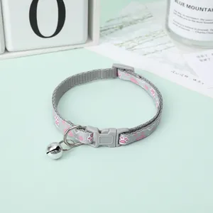 Detailed view of adjustable grey pet collar with pink paw prints and shiny silver bell