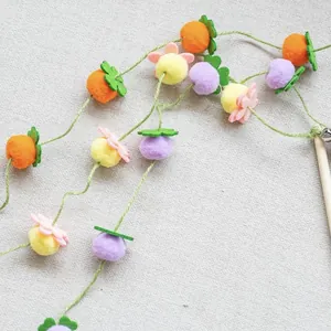 Dettaglio di pompon colorati a forma di frutta su una bacchetta in legno per gatti