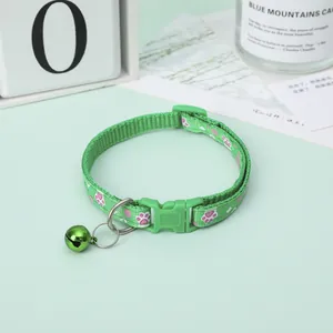 Detailed view of a green pet collar with cute paw print patterns and a small green bell.