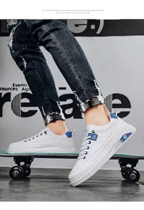 Close-up view of white men's fashion skate sneakers with blue details on a skateboard