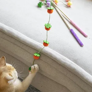 Dettaglio di un gattino che gioca con un giocattolo in feltro a forma di caco per gatti.