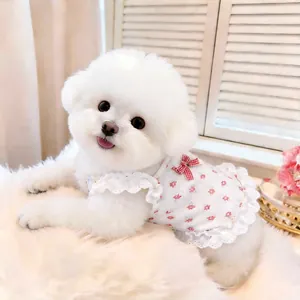 Primo piano di un cane bianco con un vestito a fiori per animali e pizzo ai bordi