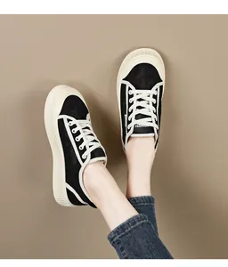 Dichtbij van zwarte ademende holle sneakers met dikke platformzolen en witte veters.