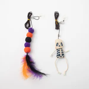 Close-up of Halloween cat toys featuring a skeleton doll and colorful feathered pom-poms.