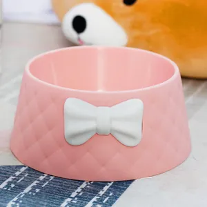 Close-up detail of a pink macaron colored pet bowl featuring a white bow and diamond texture