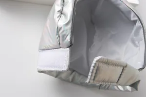 Close-up detail of white Velcro fastener on holographic silver pet astronaut space suit
