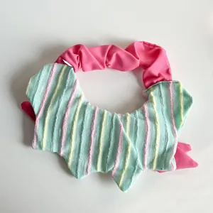 Dettaglio del bavaglio a righe verde menta per animali con fascia elastica rosa.