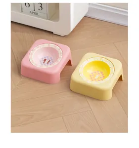 Dettaglio delle ciotole in ceramica rosa e gialla per animali con supporti inclinati