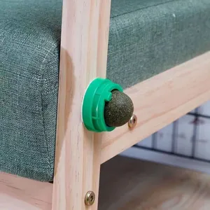 Detail of a rotating natural catnip ball toy attached to a wooden chair leg for cats