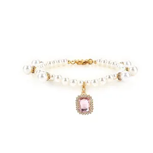 Detail view of pearl pet necklace with sparkling pink gemstone pendant and gold clasp