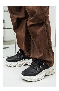Λεπτομερής προβολή ανδρικών μαύρων sneakers με χοντρές λευκές σόλες και παντελόνι