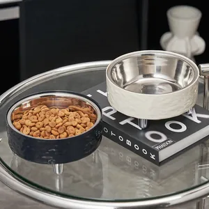 Detail of elevated stainless steel pet bowls in navy blue and cream on a modern table.