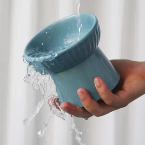 Premium blue ceramic tilted high-foot pet bowl being washed under running water for cat neck protection