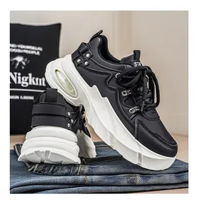 Λεπτομέρεια από κομψά ασπρόμαυρα chunky dad sneakers πάνω σε διπλωμένο μπλε τζιν παντελόνι