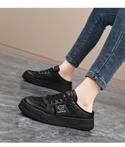 Side view of black breathable mesh mule sneakers with fashion label on marble floor