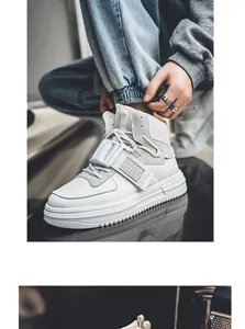 Vista dettagliata di sneakers bianche alte con un cinturino a fibbia bianco unico.