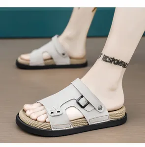 Detalle de sandalias de cuero gris para hombre con hebilla y suela de textura tejida.