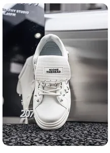 Dettaglio di sneaker punk bianche con zeppa, anelli di metallo e suola spessa.