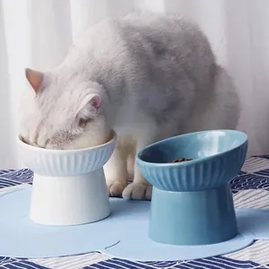 Elevated ceramic pet bowl with slanted rim for neck protection shown with feeding cat