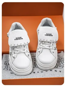 Primo piano di sneakers platform bianche punk con anelli in metallo e logo sulla lingua