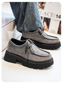 Primer plano de mocasines de ante gris con suelas gruesas de plataforma negras.