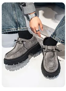 Detalle de primer plano de mocasines de ante gris para hombre con suela de goma gruesa.