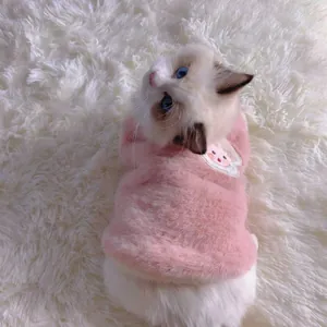 Gros plan d'un chat portant un gilet en peluche rose chaud sur un tapis blanc doux