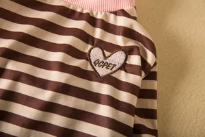 Detail of cute striped dog shirt with soft pink collar and heart patch embroidery.