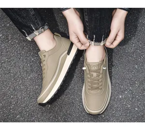 Vista dall'alto di sneakers in pelle kaki indossate con jeans neri su asfalto stradale