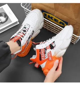 Detail view of men's white and orange chunky sneakers with fashion strap decor