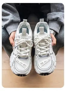 Vista superior de zapatillas chunky de malla blanca para hombre sostenidas por manos.